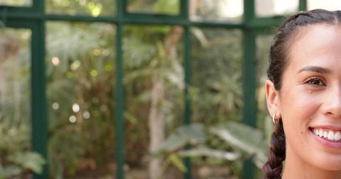 Woman with braided hair practicing yoga in glasshouse