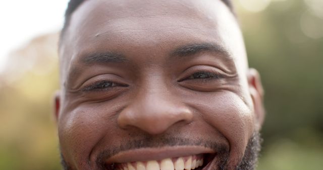 Showcasing a joyful close-up of an African American man smiling, this image captures expression and happiness. Perfect for use in advertisements, social media campaigns, mental wellness articles, or promoting positive vibes and everyday happiness.