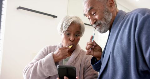 Senior Couple Brushing Teeth and Using Smartphone