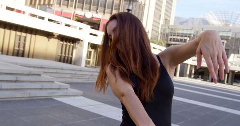Caucasian woman expressing street dance outdoors with cityscape