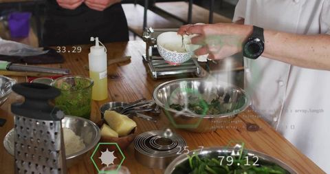 Chef sprinkling herbs into greens on wooden table with kitchen utensils and data overlays