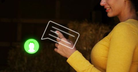 Smiling woman tapping smartphone in barn with glowing chat icon and hay bales