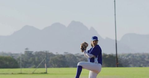 Baseball Pitcher in Action on Sunny Field Against Mountainous Backdrop