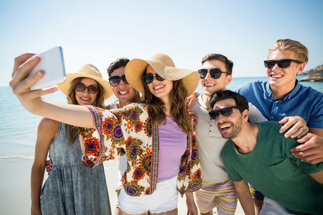 Group of cheerful friends enjoying a sunny day at the beach, taking a selfie together. Perfect for use in travel blogs, vacation advertisements, social media posts, and lifestyle articles promoting friendship, fun, and outdoor activities.