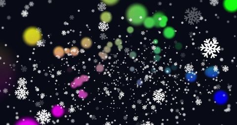 Twinkling snowflakes and colorful bokeh on dark background for festive winter designs