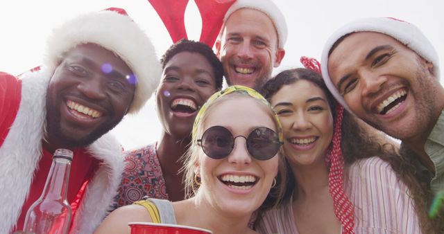 Group of friends wearing Santa hats celebrating Christmas at an outdoor BBQ party. They are laughing and enjoying each other's company, creating a joyful holiday atmosphere. Perfect for advertising holiday products, promoting joyful celebrations, and illustrating togetherness and happiness during festive occasions.