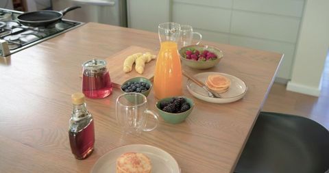 Morning breakfast spread showcasing pancakes, croissants, fresh berries and orange juice
