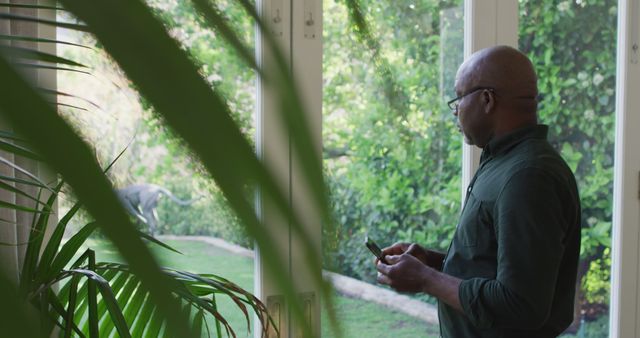 Man Looking Out Window at Backyard Garden with Smartphone - Download Free Stock Images Pikwizard.com