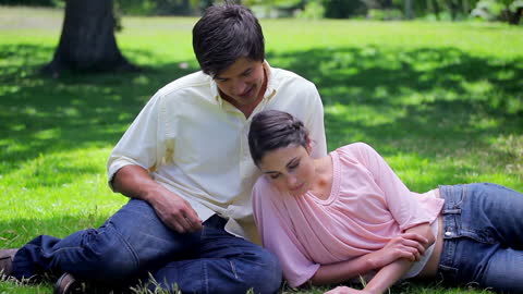 Joyful Couple Relaxing on Green Grass in Countryside