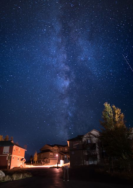 Residential neighborhood under starry night sky with the Milky Way visible. Perfect for astronomy content, real estate listings showcasing serene night views, and nature blogs highlighting the beauty of cosmic wonder.