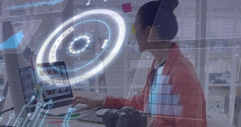 Mid-adult Asian woman working with holographic AR interface on laptop in creative studio