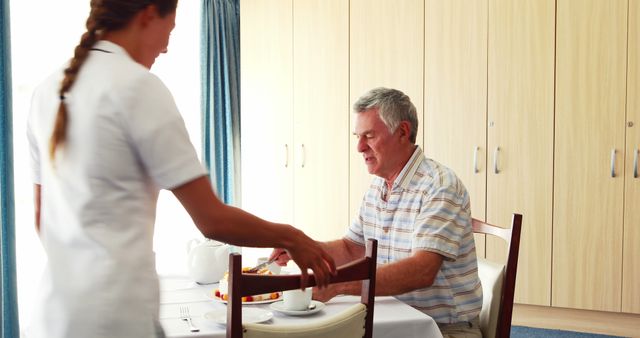 Nurse is serving a meal to an elderly man in a care home or nursing home. This scene symbolizes care, compassion, and support for seniors, emphasizing professional healthcare services in a retirement setting. Perfect for use in healthcare-related articles, marketing materials for senior care facilities, or discussions on elderly care.