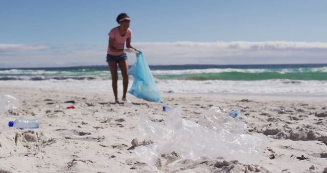African american woman collecting plastic waste on the beach. ecology environment protection and recycling concept