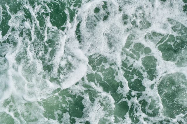 Depicts top view of turbulent ocean waves with foamy surface. Can be used for backgrounds, nature-related projects, or content emphasizing marine themes and water textures.