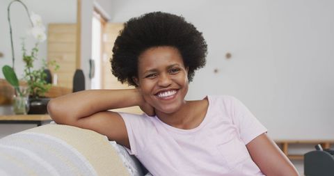 Relaxed Young Woman with Afro Hair Sitting on Sofa - Download Free Stock Images Pikwizard.com
