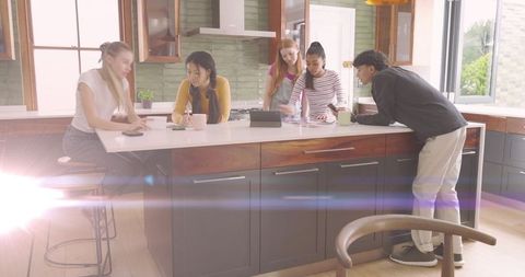 Young adults brainstorming around modern kitchen island, collaborating with tablet and notes