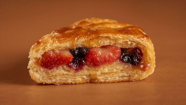 Glazed berry-filled puff pastry featuring flaky laminated layers and caramel drizzle