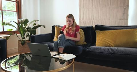 Teen Girl Excitedly Using Smartphone on Comfortable Living Room Sofa
