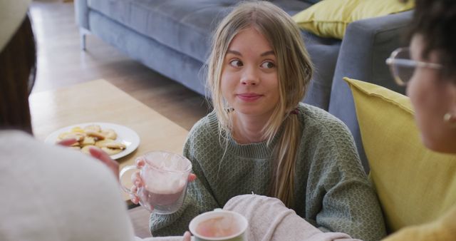 Happy diverse teenager girls sitting on sofa, drinking cocoa - Download Free Stock Photos Pikwizard.com