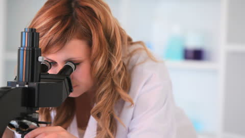Young Scientist Examining Sample Through Microscope in Laboratory