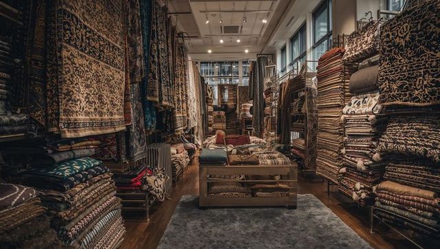 Cozy artisan rug shop interior displaying stacked patterned carpets, cushions and textiles