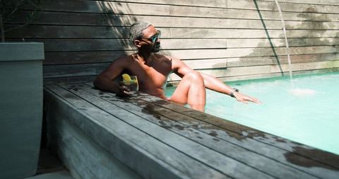 Man Relaxing in Plunge Pool with Cocktail in Tranquil Spa Environment