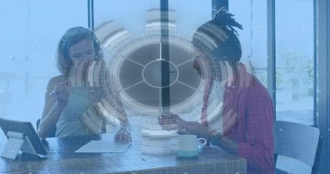 Two colleagues reviewing documents and tablet with futuristic hud overlay in modern office