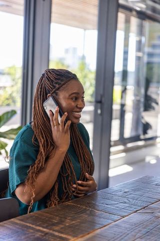 Happy professional woman talking on smartphone in modern office