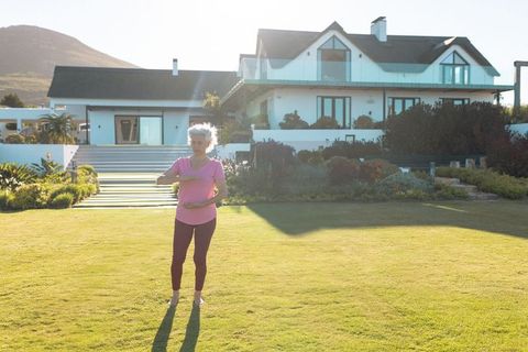 Senior Woman Practicing Tai Chi in Front of Modern Home