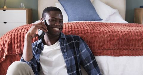 Man Relaxing on Bedroom Floor Talking on Smartphone