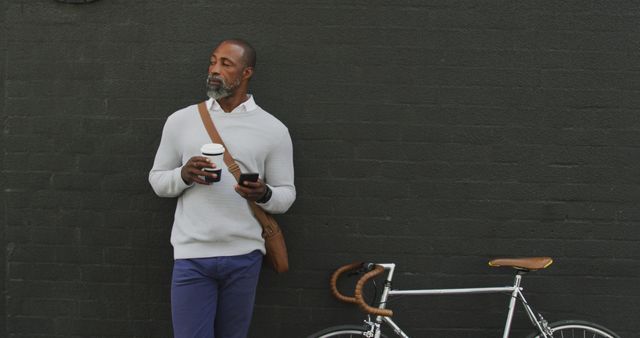 Stylish Mature Man with Coffee and Bicycle Against Black Wall - Download Free Stock Images Pikwizard.com