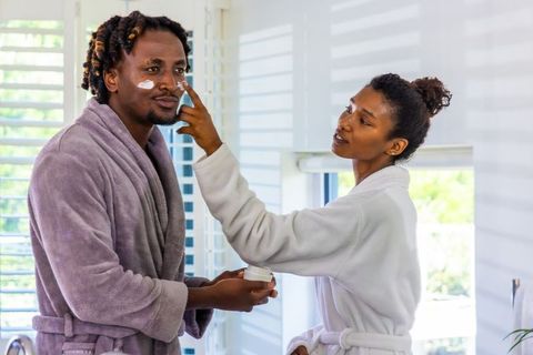 African american couple applying facial moisturizer morning skincare ritual sunlit bathroom