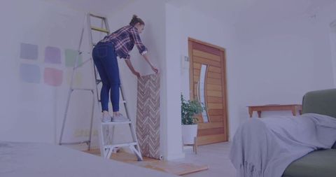 Woman Renovating Living Room with Modern Wallpaper and Color Swatches