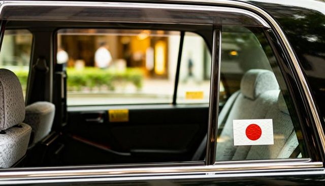 Black sedan rear passenger interior showing japanese flag sticker on window