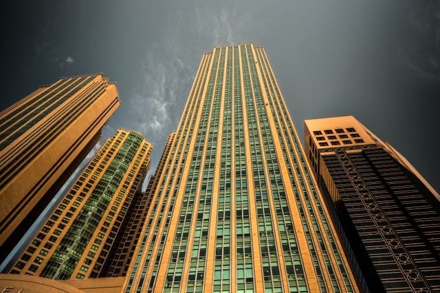 Modern skyscrapers dominate this urban cityscape under a dramatic sky. Tall buildings with glass windows create an imposing and modern skyline, perfect for depicting business districts or corporate settings. Ideal for articles, advertisements, or presentations focused on real estate, city living, and architecture.