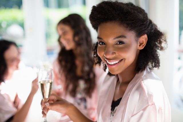 Women enjoying a casual gathering at home, drinking champagne and smiling. Perfect for use in lifestyle blogs, social media posts, advertisements for home entertainment products, or articles about friendship and celebrations.