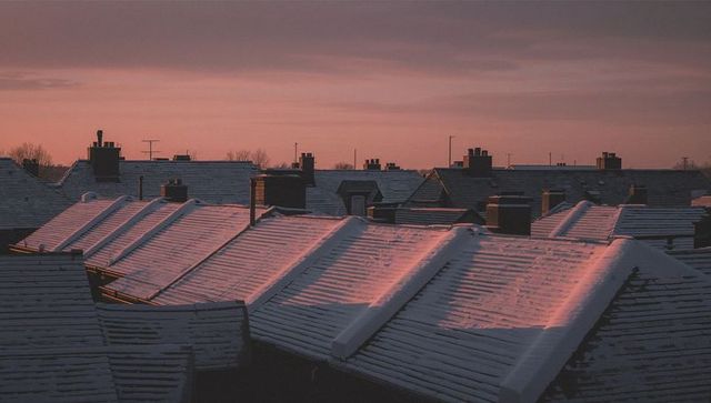 Snow-covered terraced rooftops gleaming under sunrise light over winter urban skyline
