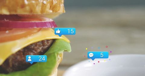 Gourmet cheeseburger with social media engagement badges popping over wooden table