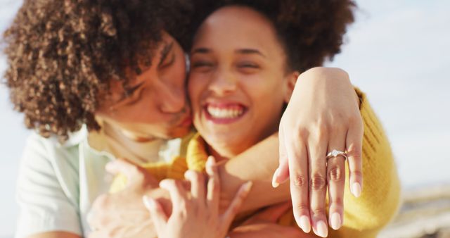Engaged couple celebrating their engagement with a close-up of the engagement ring outdoors. Perfect for use in relationship blogs, engagement announcements, wedding planning websites, and romantic greeting cards.