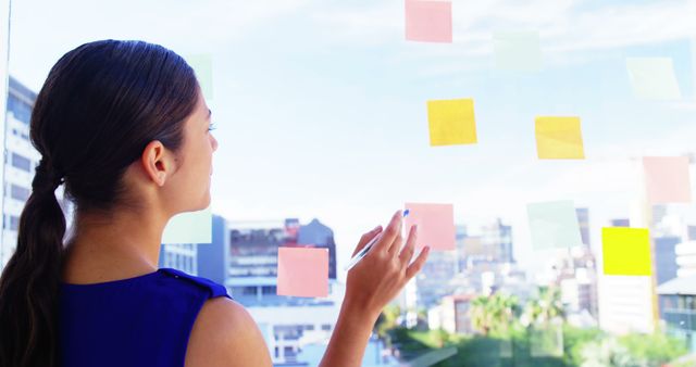 Businesswoman Organizing Sticky Notes on Large Office Window - Download Free Stock Images Pikwizard.com