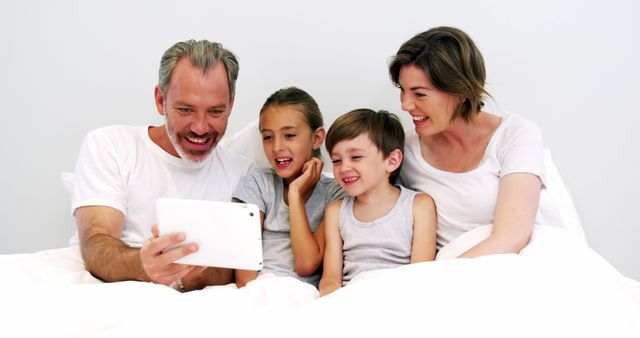 Happy Family of Four Watching Tablet Together in Bed - Download Free Stock Images Pikwizard.com