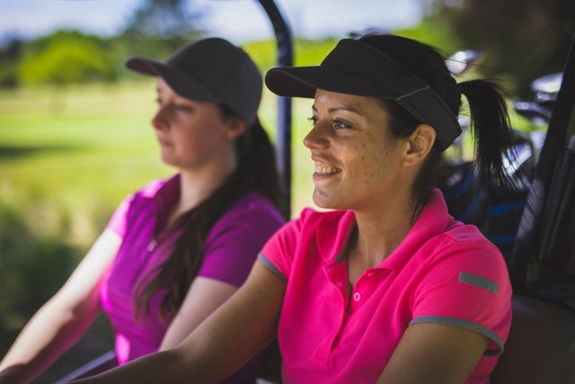 Two women enjoying a sunny day driving a golf cart on a golf course. Ideal for promoting sports, active lifestyle, outdoor activities, and leisure. Perfect for use in advertisements, brochures, and websites related to golf, sports clubs, and recreational activities.