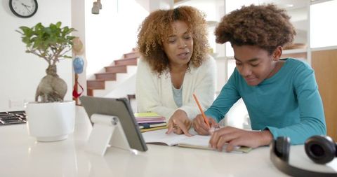 Mother Assisting Son with Homework in Kitchen Setting