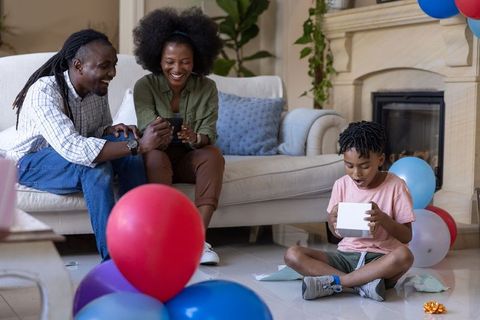 African american family celebrating at home with child opening gift while parents smile
