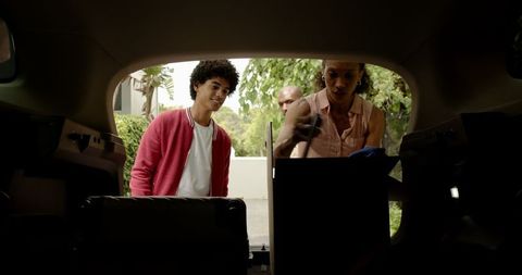 Family packing car trunk for road trip vacation