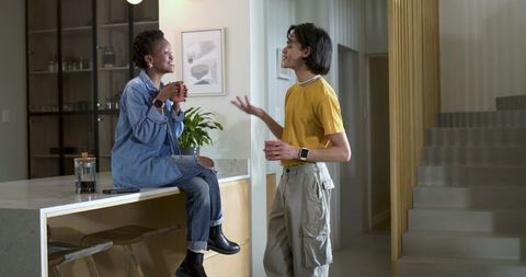 Diverse housemates chatting over coffee on kitchen island in modern minimalist home