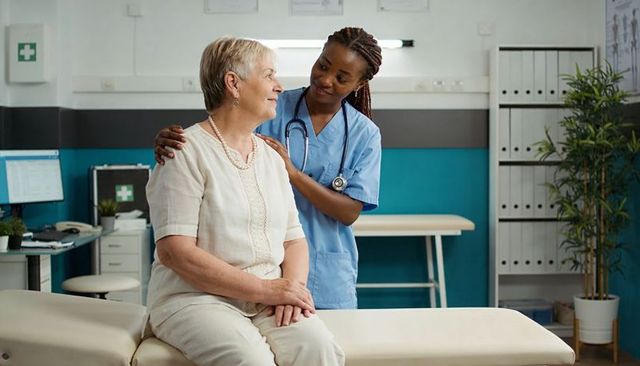 Nurse comforting senior woman on clinic exam couch providing compassionate care and support