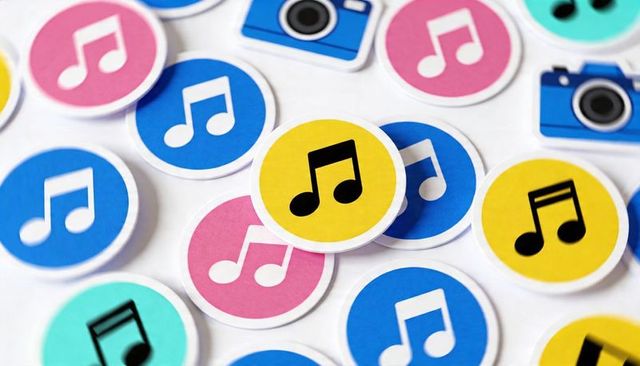Scattering colorful music note and camera stickers on white tabletop for media design