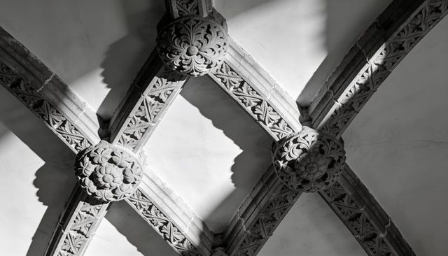 Gothic vaulted ceiling with carved ribbed arches and floral bosses in monochrome chapel