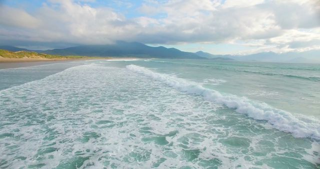 A tranquil beach scene with gentle waves and distant mountains invites peaceful contemplation. - Download Free Stock Photos Pikwizard.com